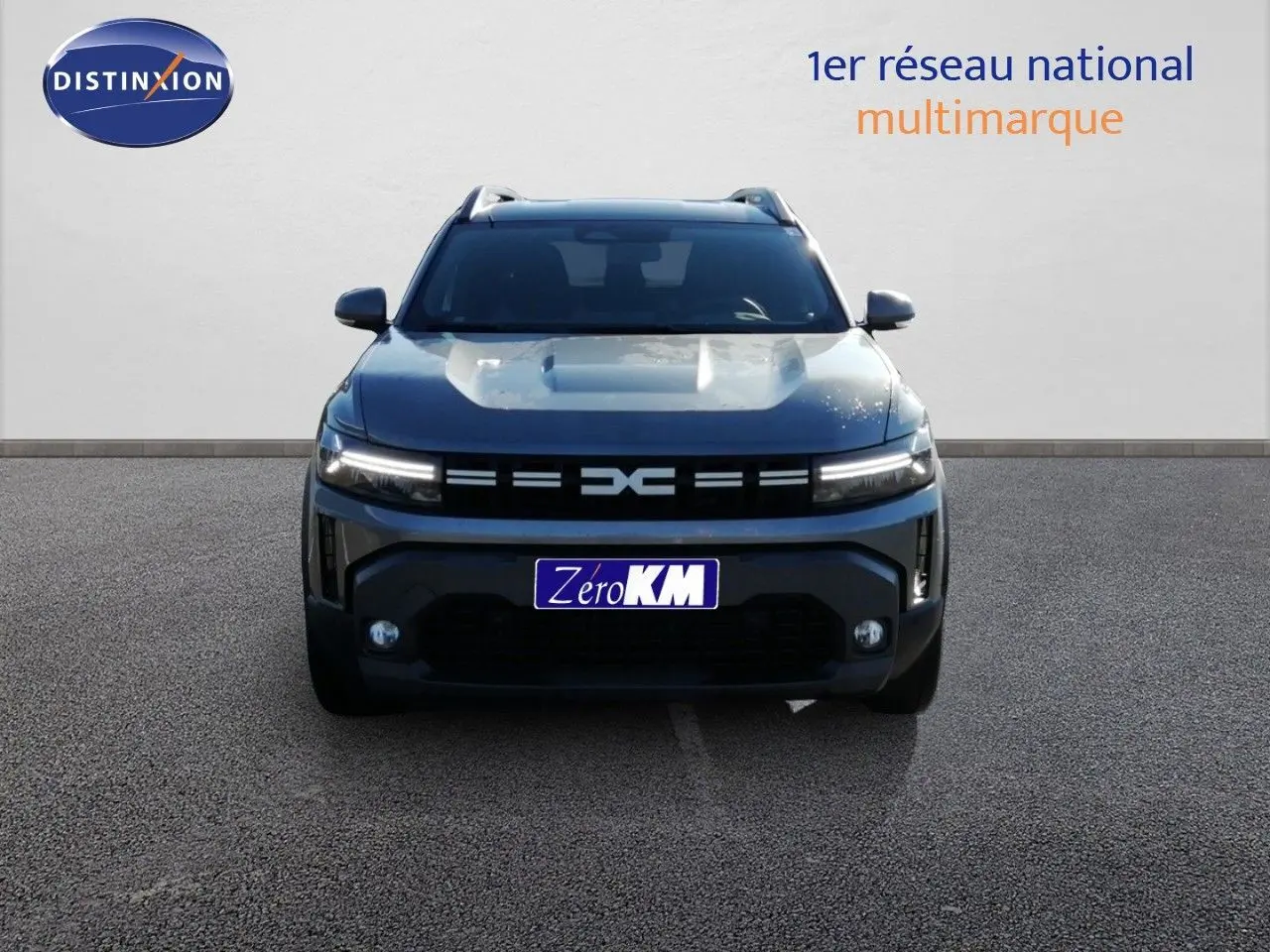 Vue frontale d'un Dacia Duster TCE MHEV 140CH Journey gris schiste métal avec calandre noire distinctive et feux LED allumés.