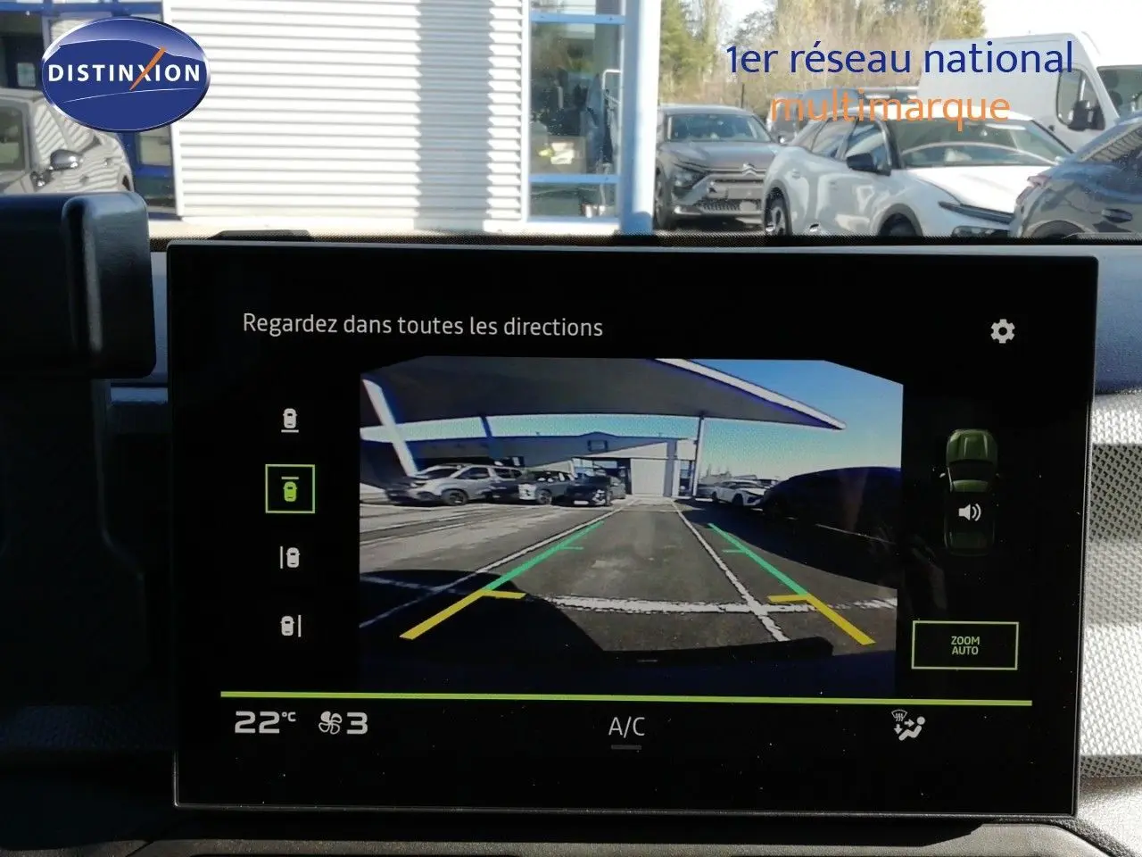 Vue de l'écran intérieur montrant la caméra de recul du Dacia Duster gris schiste métal en stationnement extérieur.