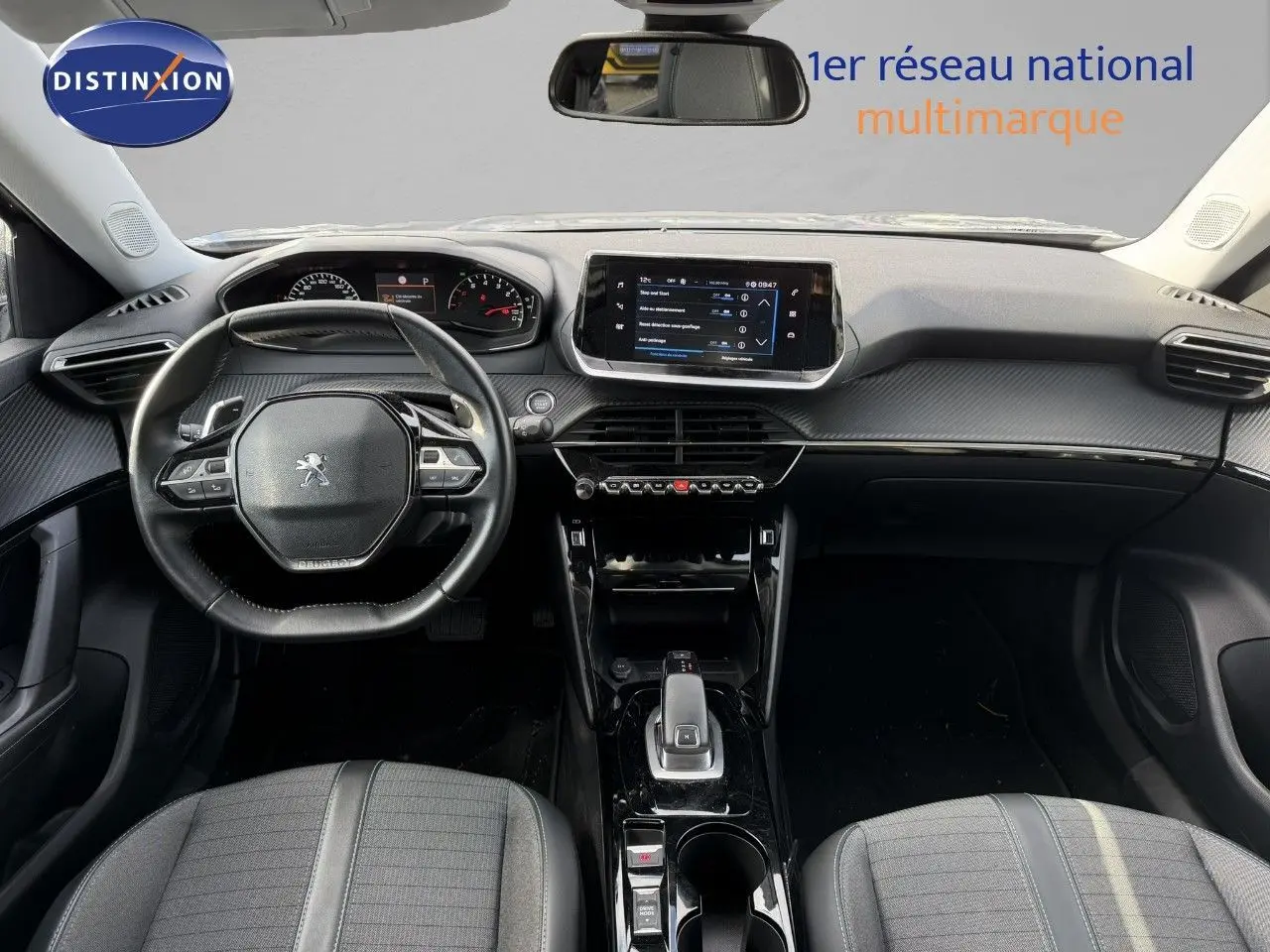 Vue intérieure frontale du tableau de bord et volant noir du Peugeot 2008 gris Artense avec écran tactile central et console brillante.