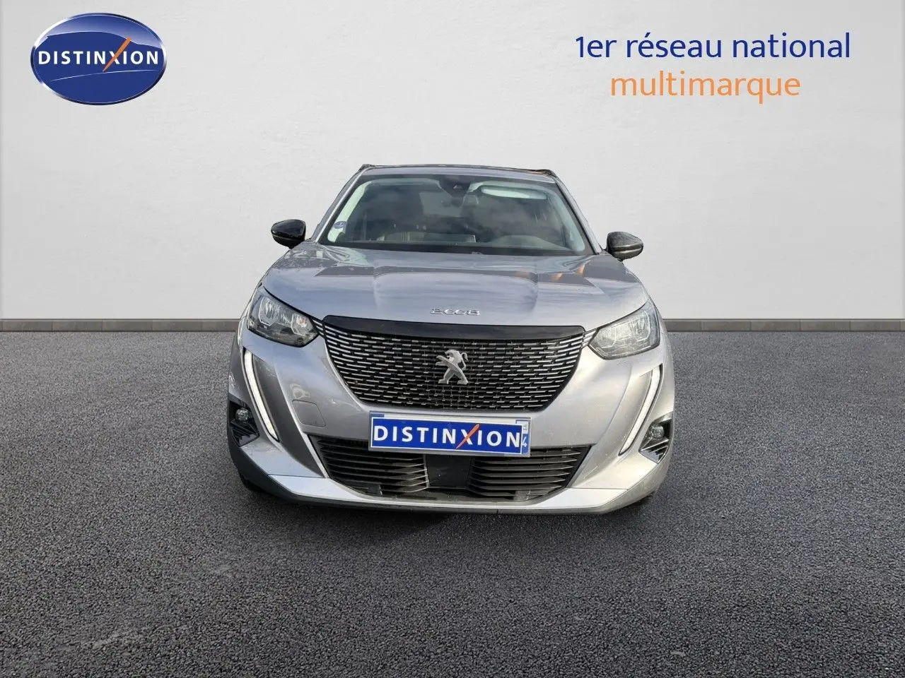 Vue avant d'un Peugeot 2008 gris Artense 2022 avec calandre noire et phares LED allumés.