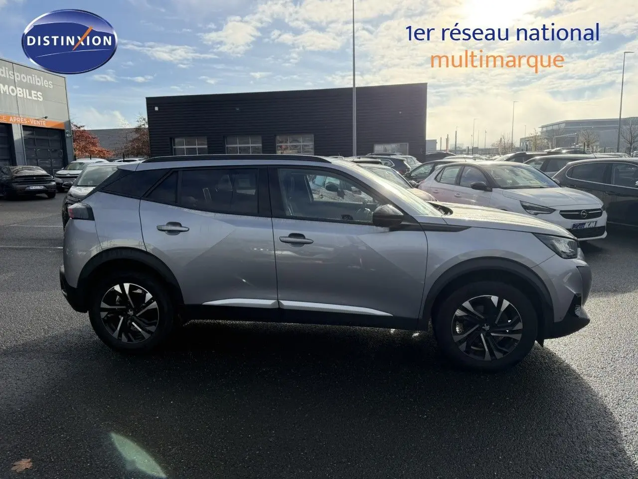 Profil droit d'un Peugeot 2008 gris Artense 2022 avec jantes noires et toit noir, stationné en extérieur par temps ensoleillé.