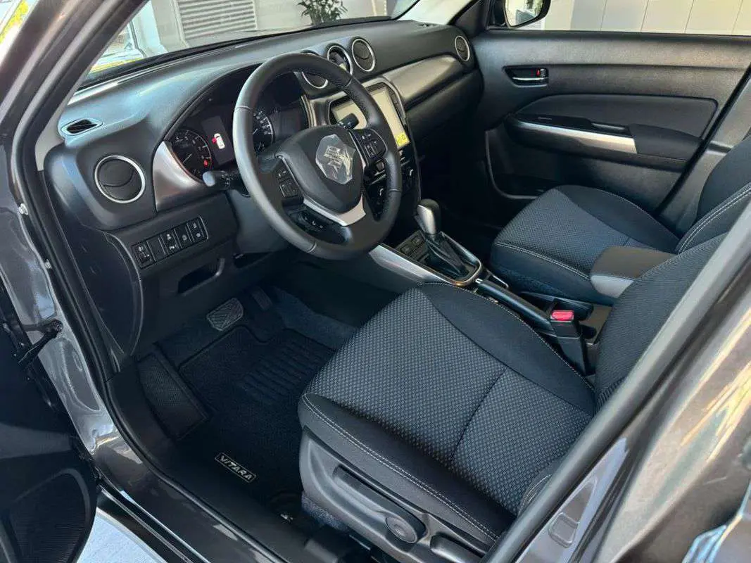 Intérieur avant droit du Suzuki Vitara 2025 hybride, sièges noirs, volant multifonction et console centrale avec boîte auto.