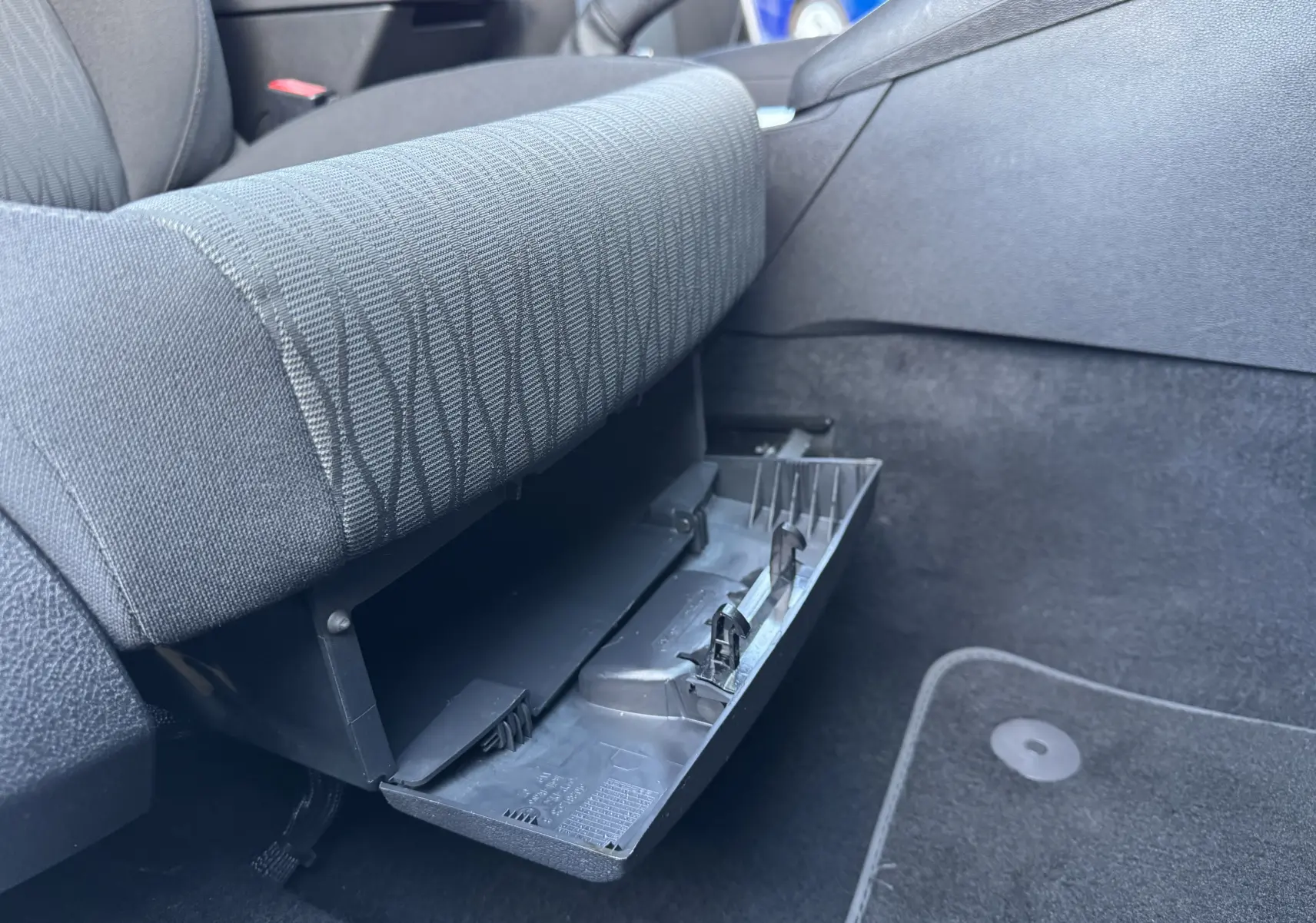 Gros plan sur la boîte à gants ouverte côté passager d'une SEAT LEON gris 2016, intérieur tissu noir.