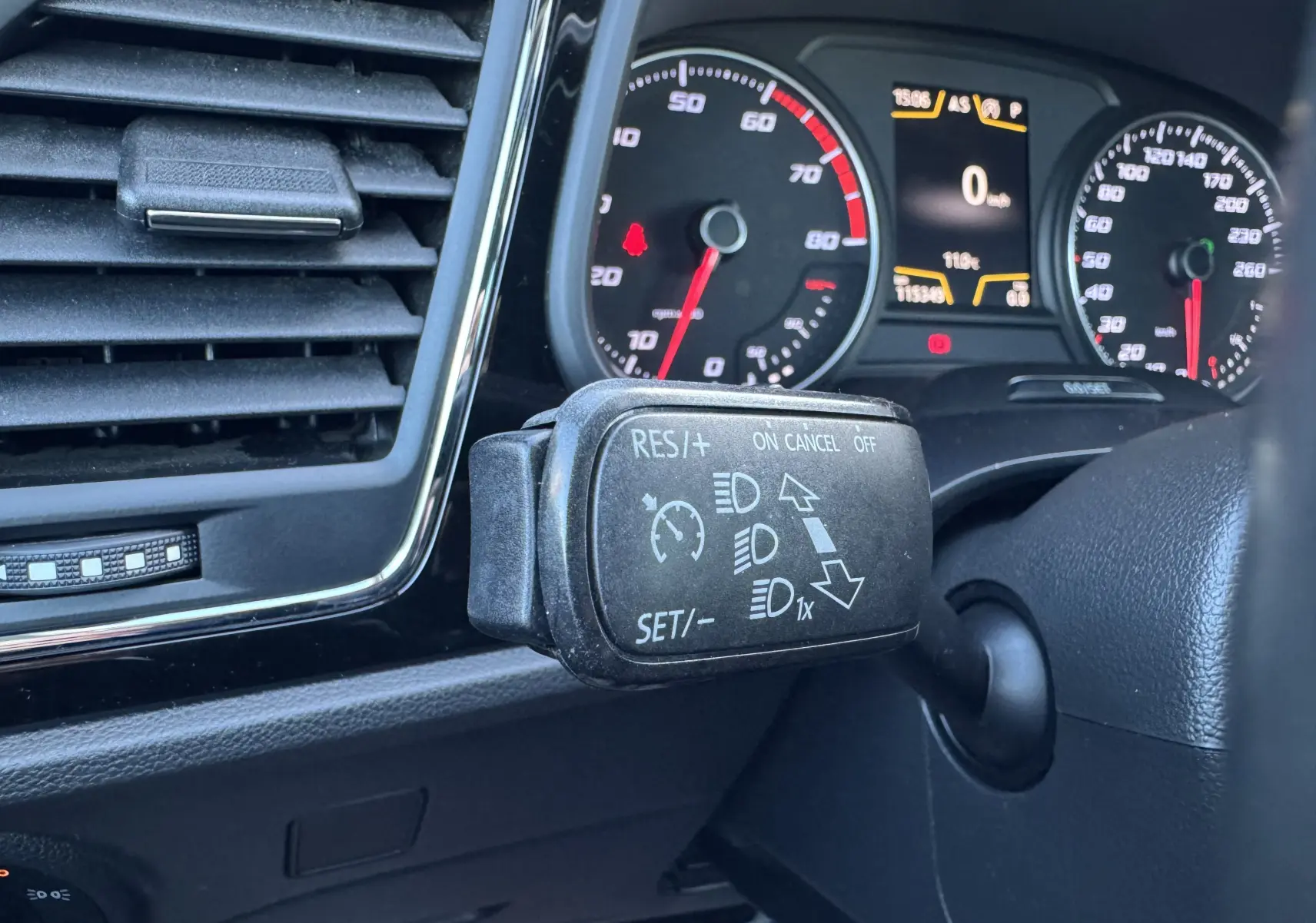 Gros plan sur la commande de régulateur de vitesse à gauche du volant dans le tableau de bord gris du SEAT Leon 2016.