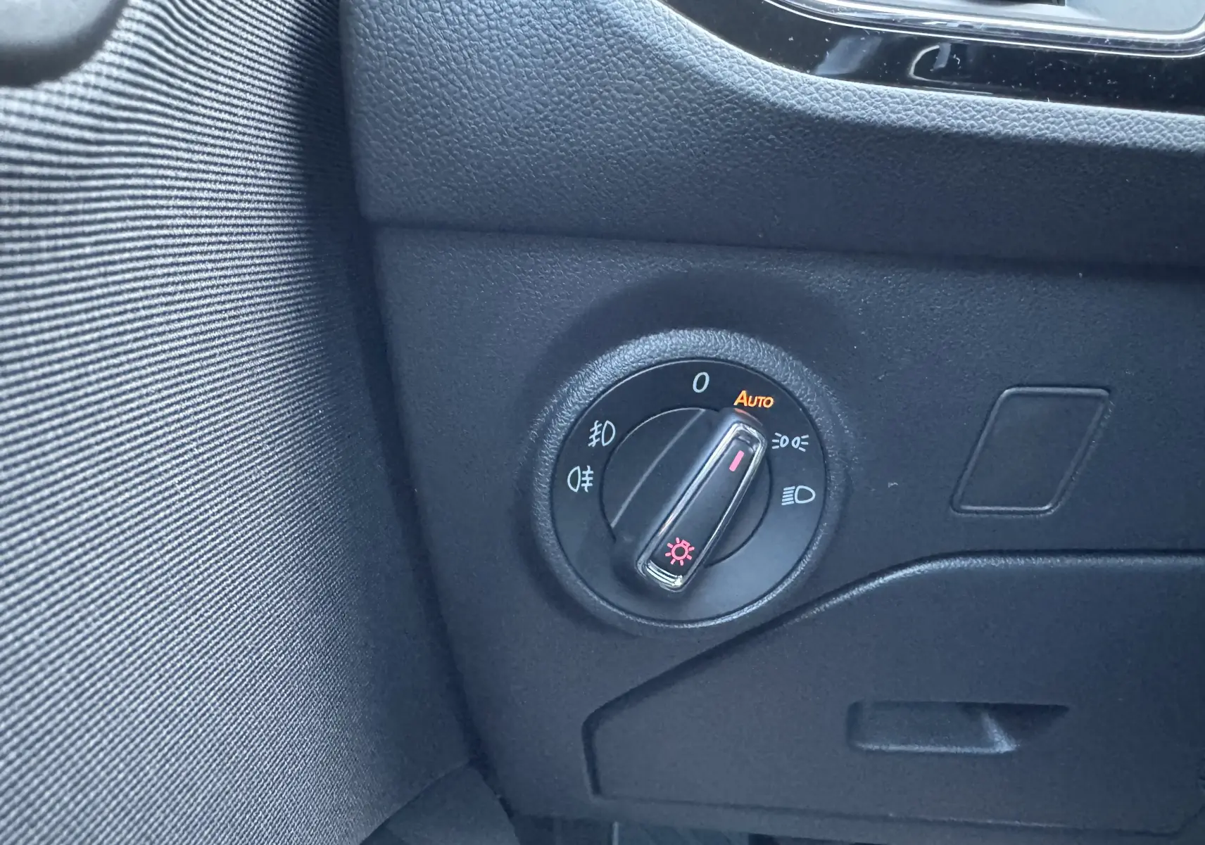 Gros plan sur le bouton de commande des phares dans l'habitacle noir d'une SEAT LEON gris 2016.