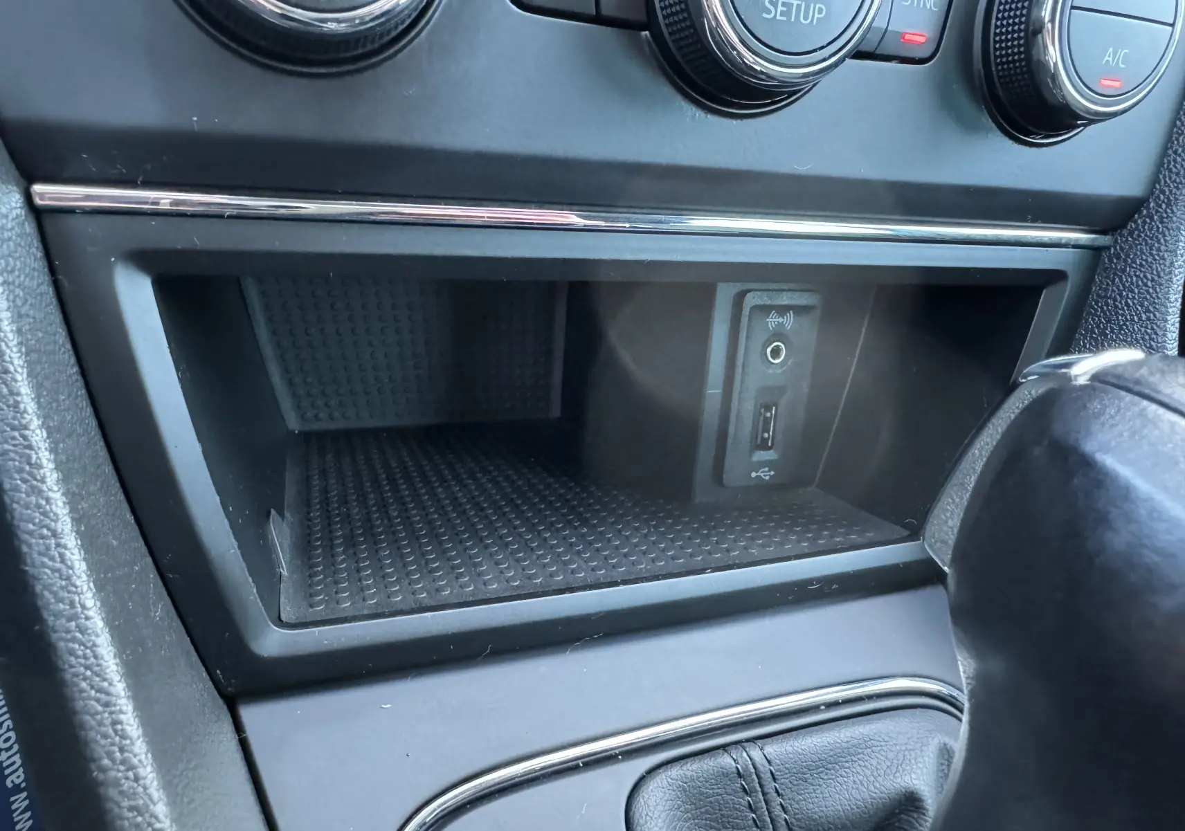 Gros plan sur la console centrale noire d'une SEAT Leon 2016, montrant prise USB et commandes de climatisation.