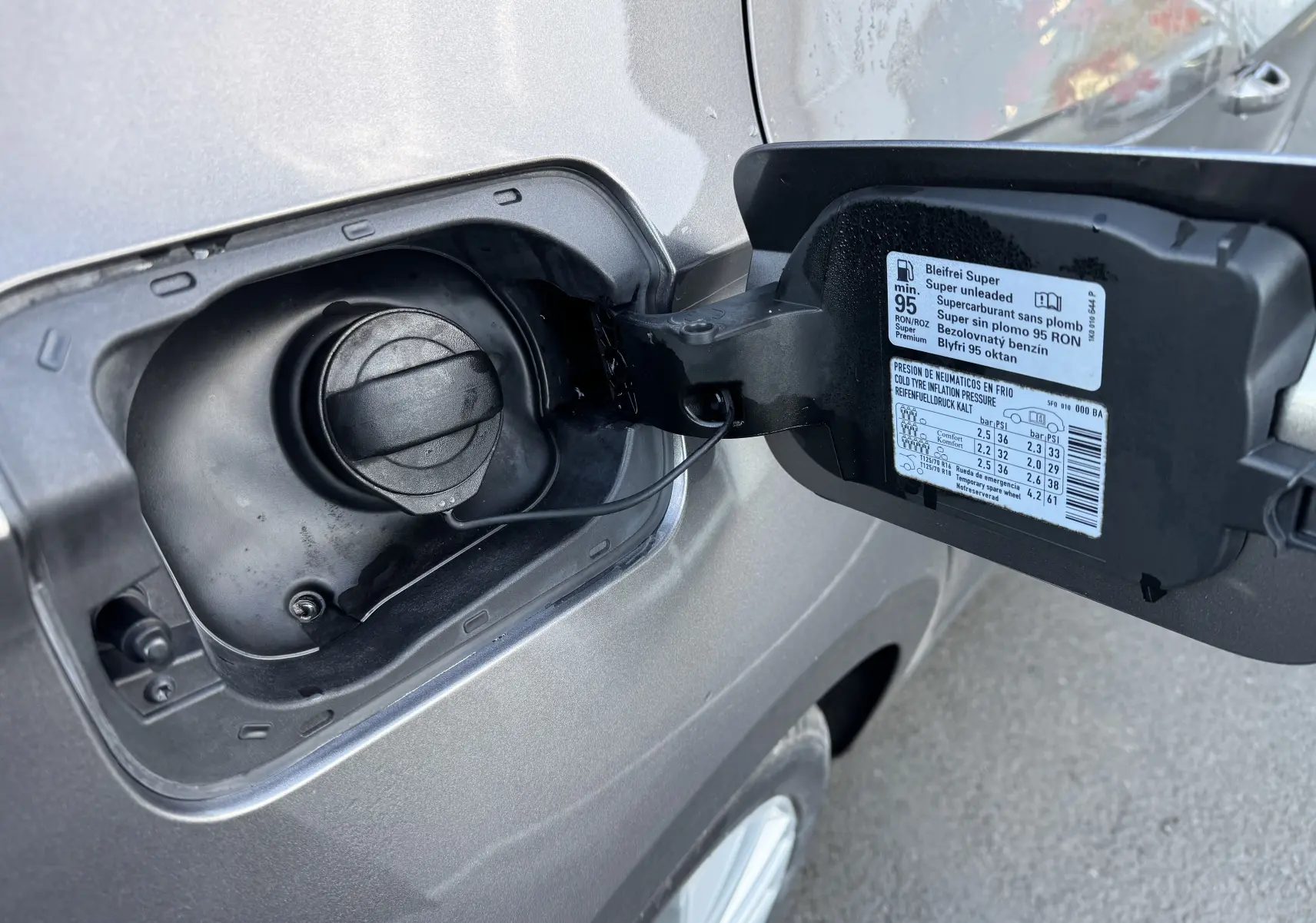 Bouchon de réservoir essence ouvert sur le côté gauche d'une SEAT Leon gris 2016, avec étiquette de pression pneus visible.