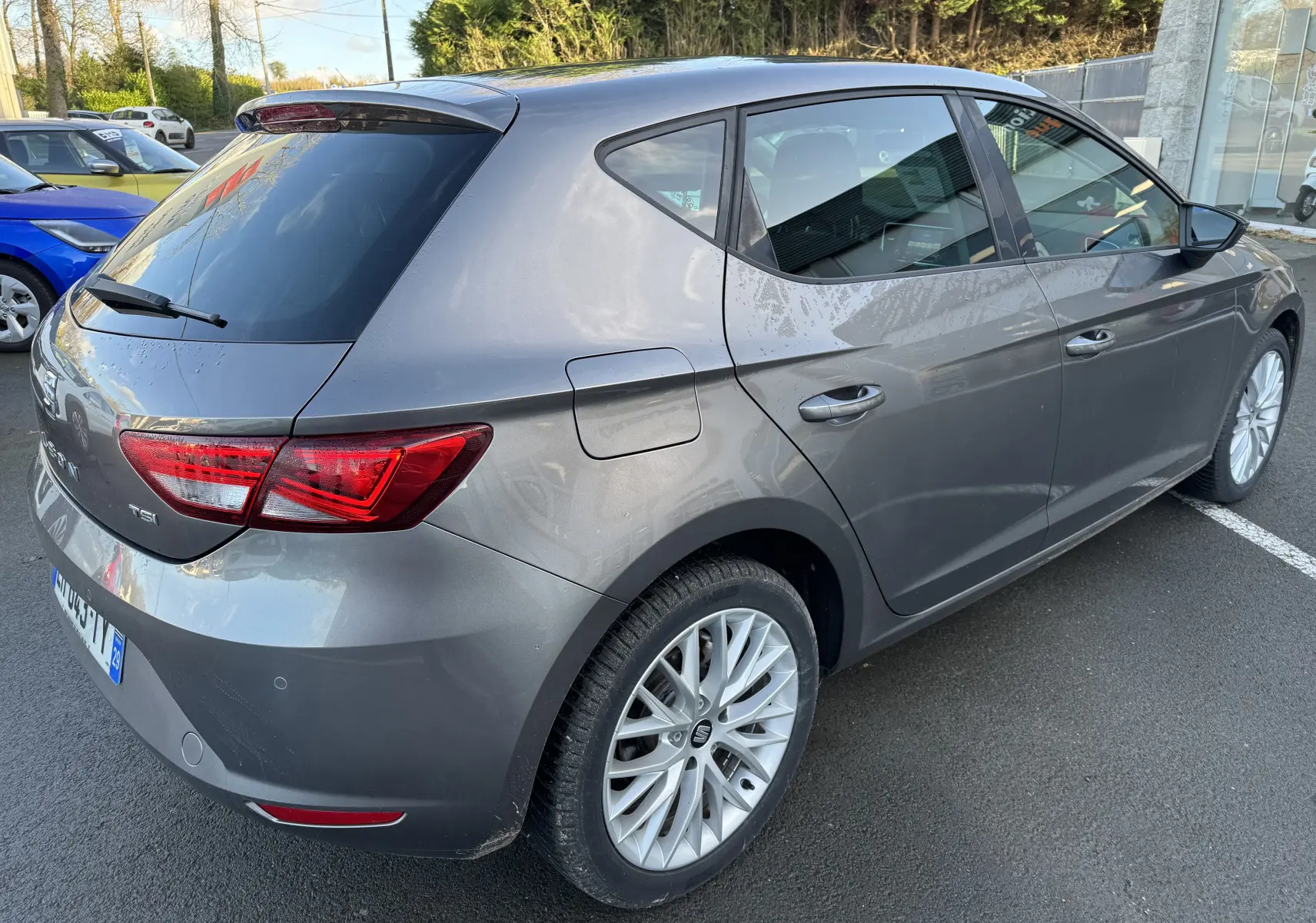 Vue 3/4 arrière droite d'une SEAT Leon gris métallisé, avec jantes alliage et feux arrière LED distinctifs.