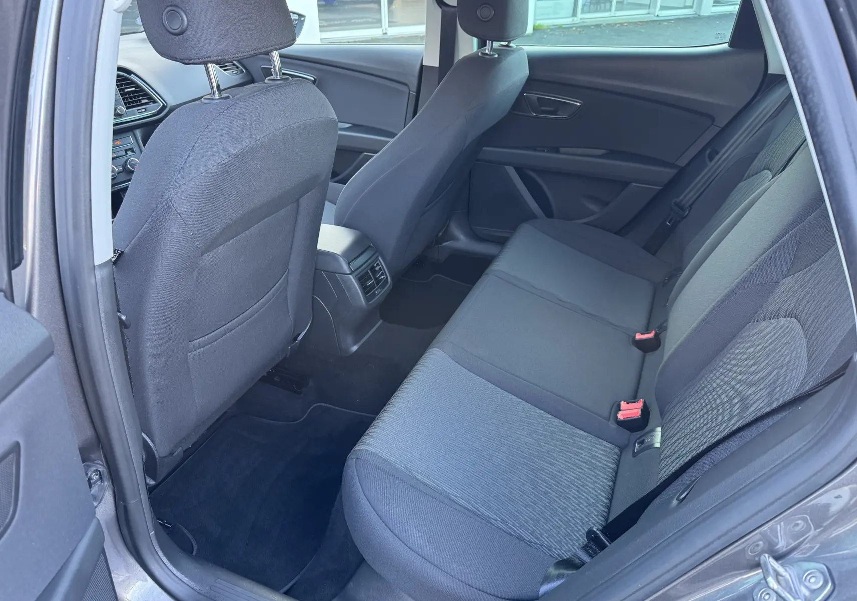 Vue intérieure côté droit sur la banquette arrière grise du SEAT LEON 2016 avec sièges tissu et ceintures visibles.
