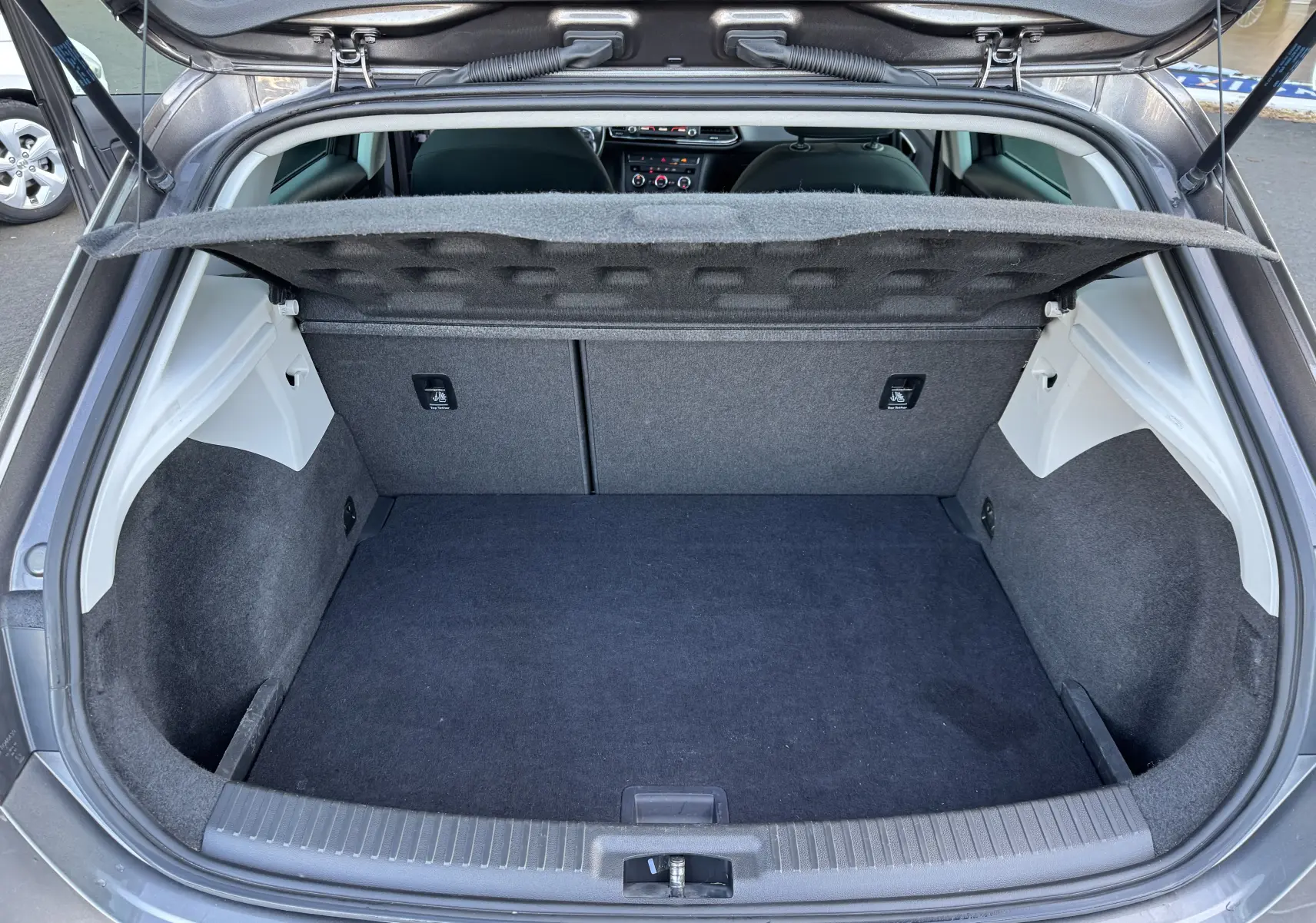 Coffre ouvert d'une SEAT LEON gris 2016, vue arrière montrant l'espace de chargement et la tablette cache-bagages relevée.