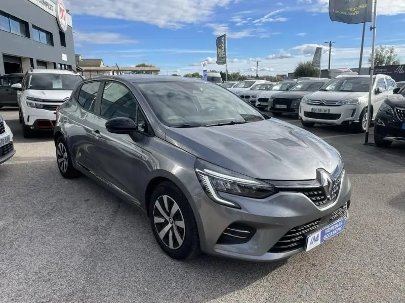 Renault Clio V TCE 90 X-TRONIC gris foncé métal vue 3/4 avant droit sur parking de voitures d'occasion.