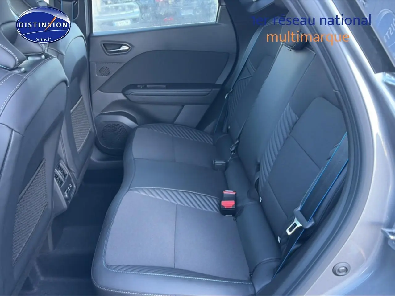 Vue intérieure côté droit montrant la banquette arrière noire avec surpiqûres bleues du Renault Captur hybride 2025.