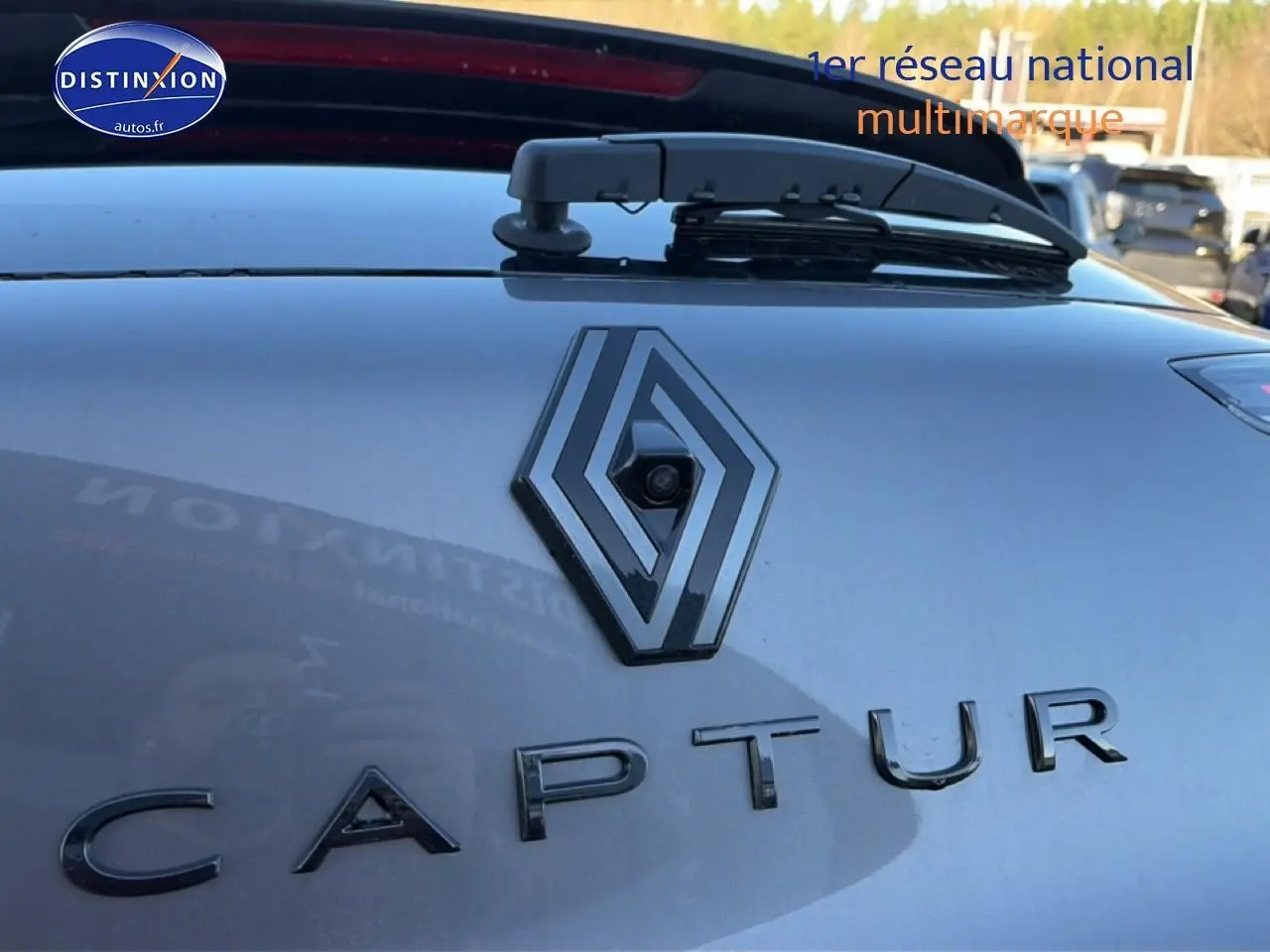 Gros plan sur le logo Renault et l'inscription Captur sur la partie arrière gris cassiopée du véhicule.