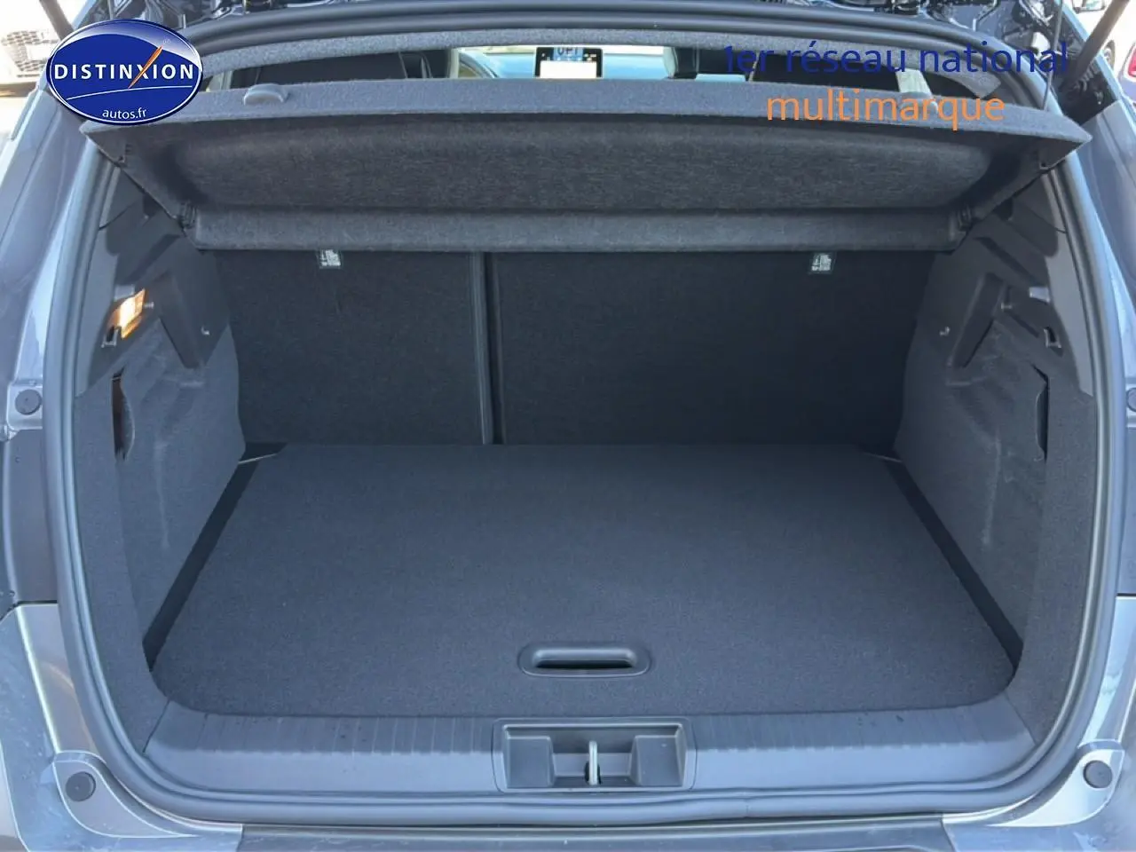 Coffre ouvert vu de l'arrière d'un Renault Captur gris cassiopée, montrant un espace de chargement propre et vide.