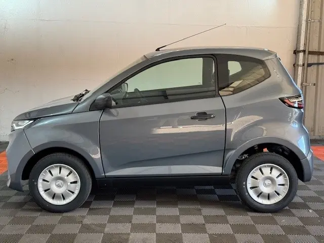 Vue de profil côté gauche d'une Aixam Ambition 0.5 City Pack gris foncé avec rétroviseur caméra côté conducteur.