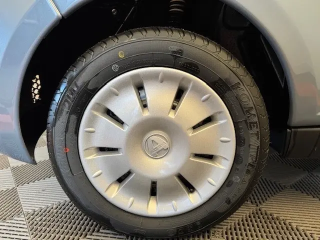 Gros plan sur la roue avant droite d'une Aixam Ambition 0.5 City Pack gris foncé avec jante et logo central.