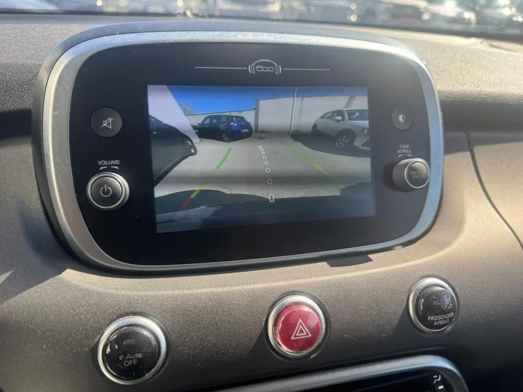 Écran central de la FIAT 500X MY23 montrant la caméra de recul avec vue arrière sur un véhicule bleu.