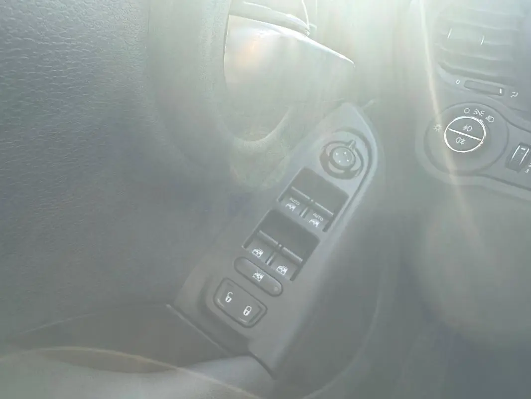 Détail des commandes des vitres électriques et réglage des rétroviseurs sur la porte côté conducteur d’un FIAT 500X bleu.