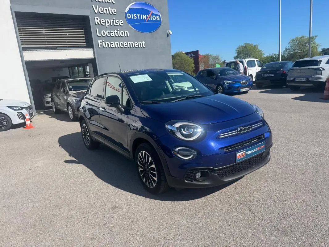 Fiat 500X bleu vue 3/4 avant droit, avec jantes 16 pouces et phares ronds distinctifs, stationnée en extérieur.