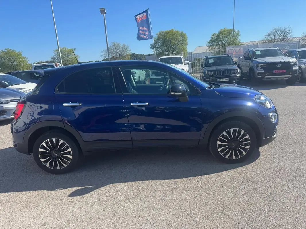 Fiat 500X bleu vue de profil côté gauche, jantes classiques 16 pouces et rétroviseurs noirs brillants.