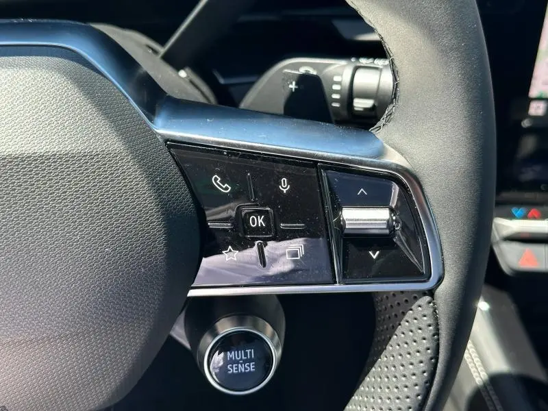 Gros plan sur les commandes multifonctions côté gauche du volant noir du Renault Austral blanc nacré 2025.