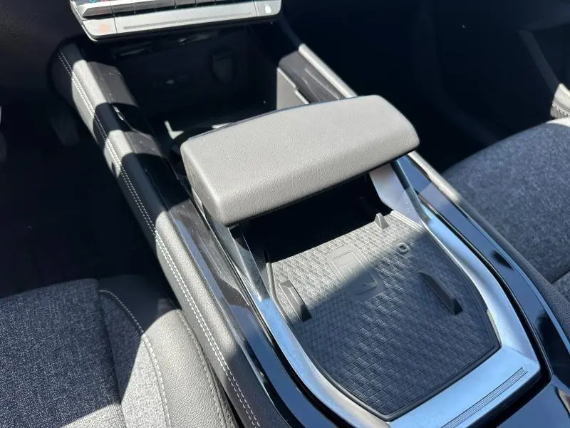 Vue rapprochée de l'accoudoir central noir et de la console brillante du Renault Austral blanc nacré 2025.