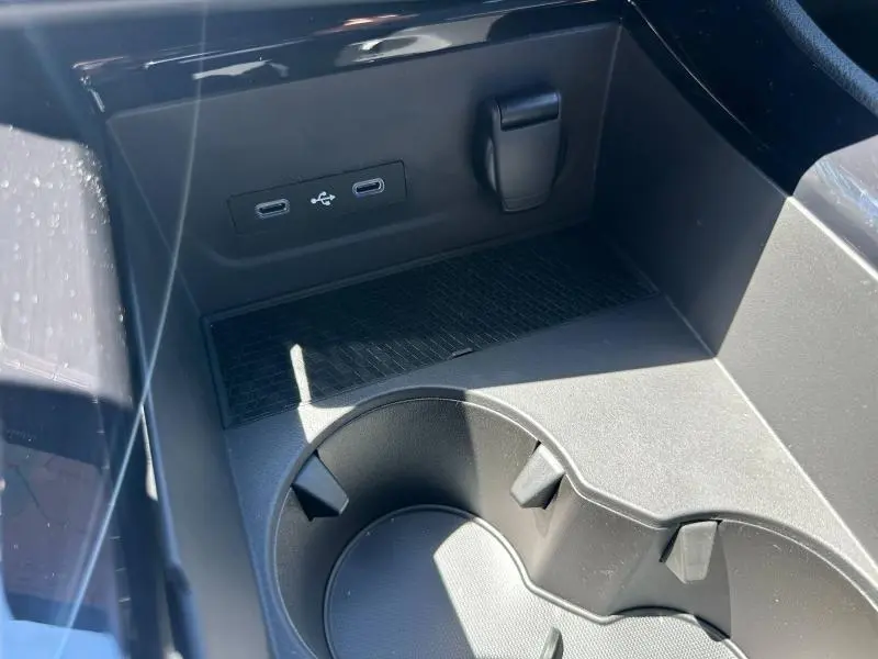 Gros plan sur la console centrale noire du Renault Austral 2025, montrant prises USB-C et porte-gobelets intégrés.