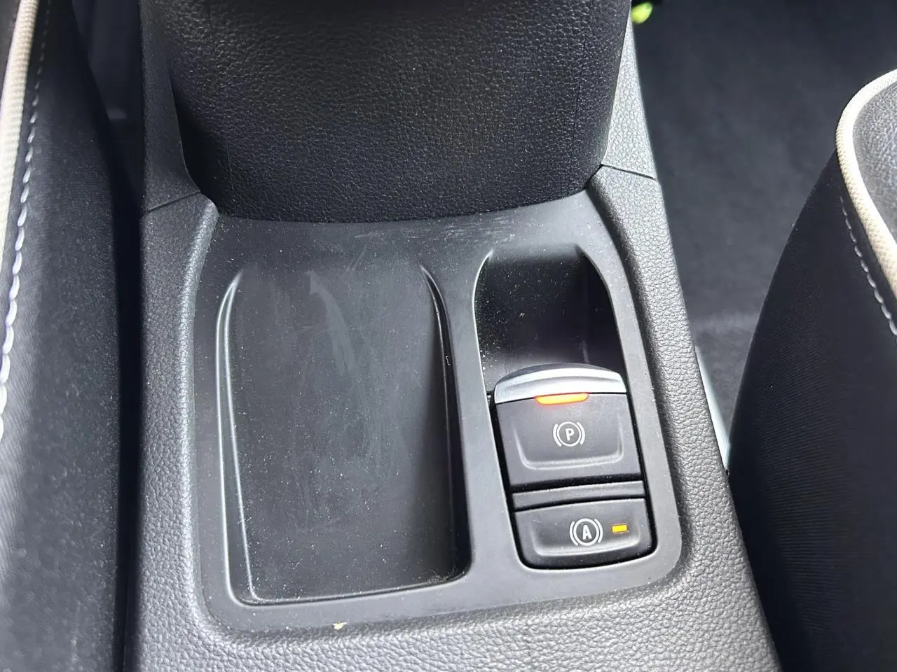Gros plan sur la console centrale noire avec boutons frein de parking et aide au démarrage Renault Clio 2025.