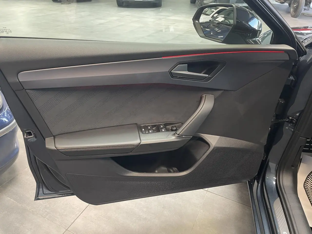 Vue côté gauche de la porte avant gris foncé de la CUPRA Leon 2026 avec insert suédine et surpiqûres cuivrées.