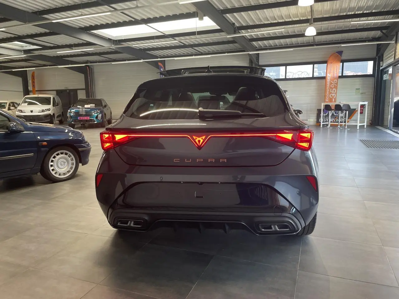 Vue arrière d'une CUPRA Leon gris magnétique avec feux arrière Tri-LED et double sortie d'échappement noire stylisée.