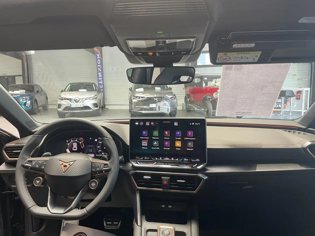Vue intérieure frontale du tableau de bord de la CUPRA Leon 2026 avec écran tactile HD et volant cuir noir au logo cuivré.