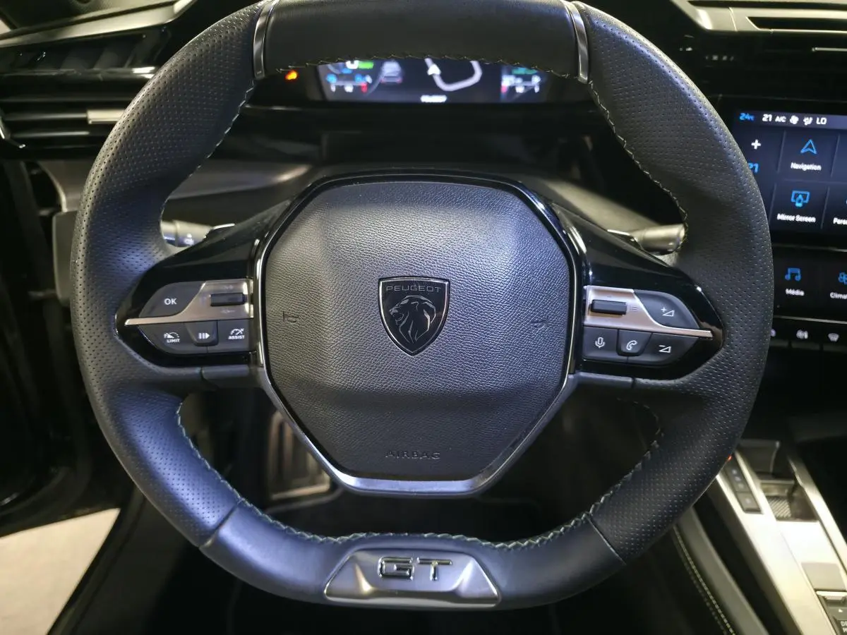 Volant cuir noir de Peugeot 308 SW GT 2024 avec logo lion et badge GT en vue frontale rapprochée.