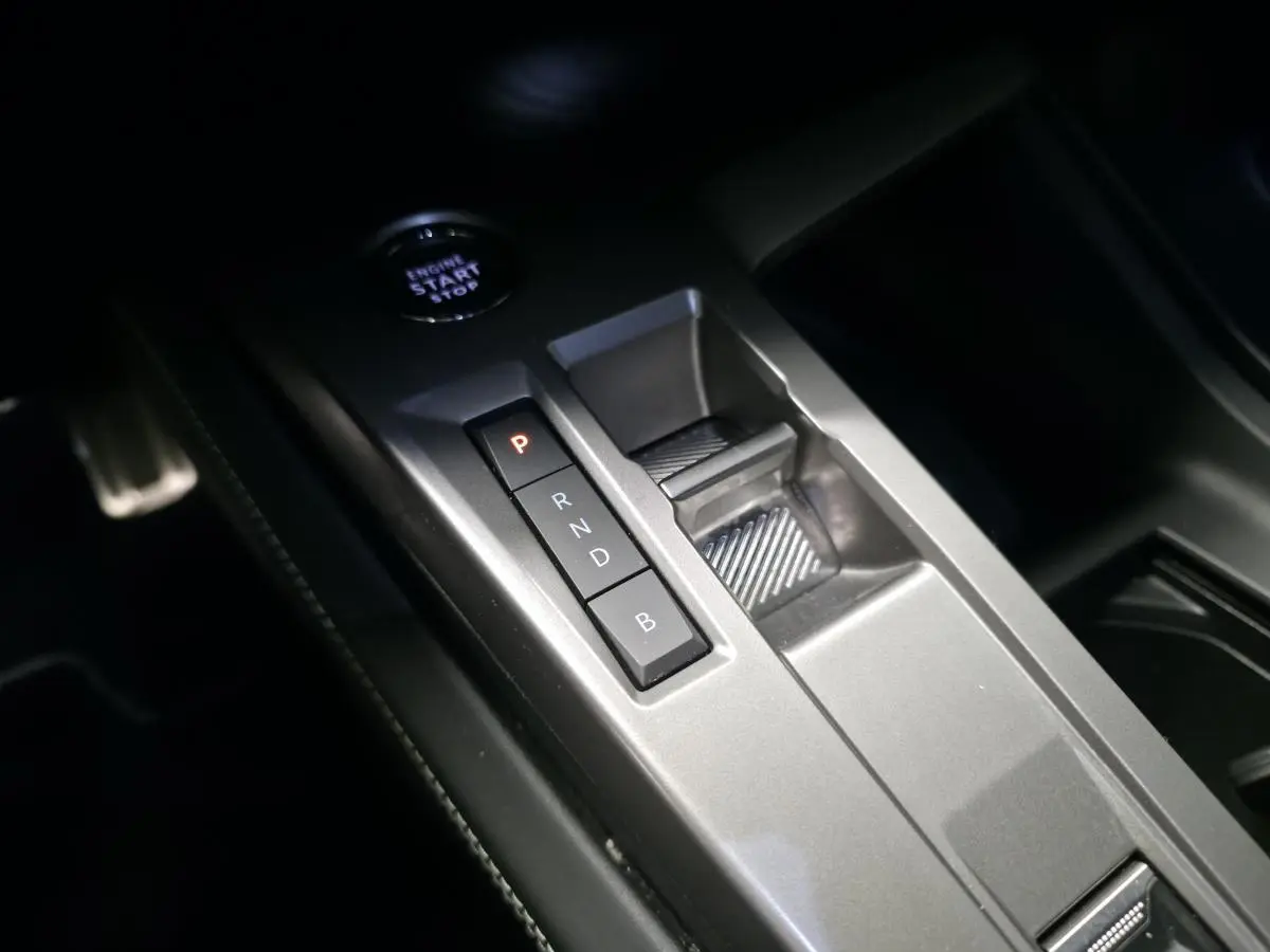 Vue rapprochée de la console centrale grise avec sélecteur de boîte automatique et bouton start/stop dans une Peugeot 308 SW noire.
