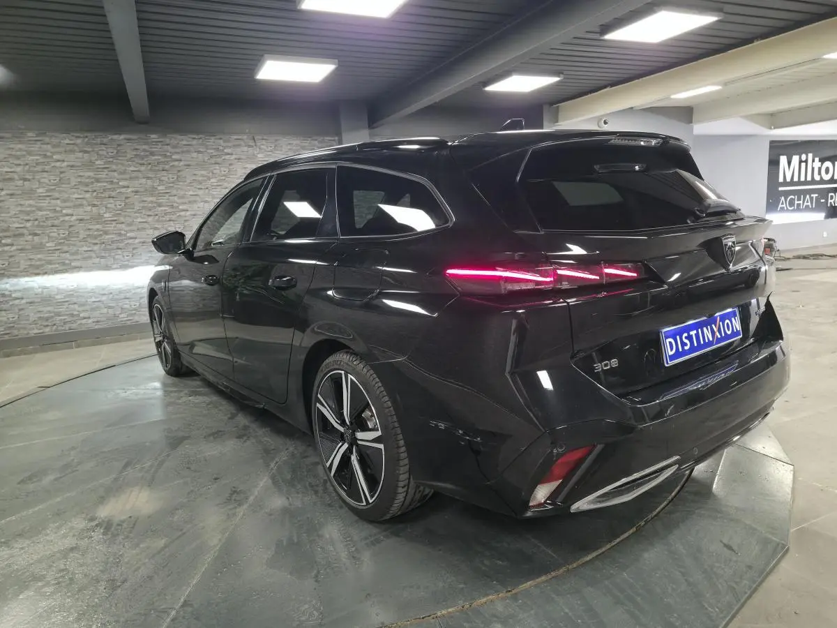 Vue 3/4 arrière droite d'une Peugeot 308 SW noire 2024 avec feux arrière LED et jantes alliage 18 pouces.