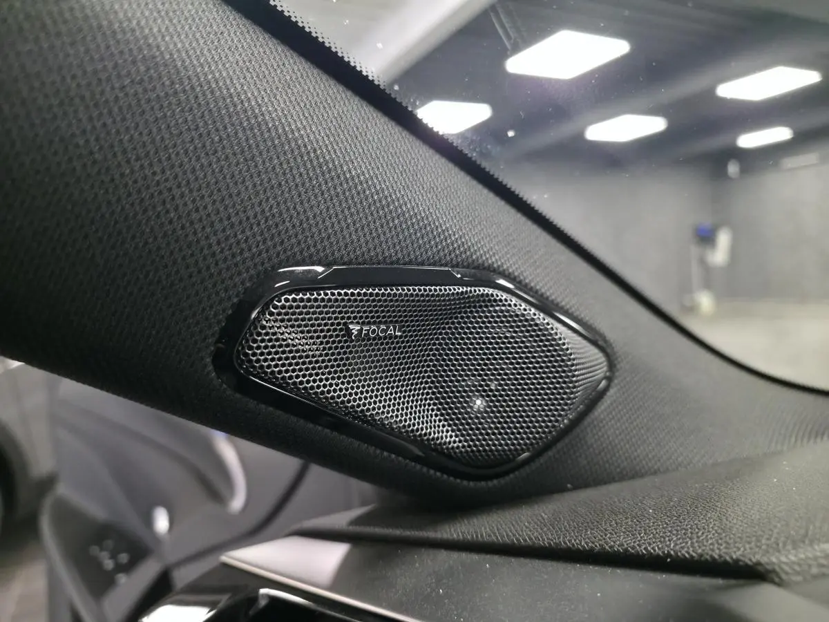 Gros plan sur le haut-parleur Focal noir intégré à la garniture intérieure côté gauche d'une Peugeot 308 SW noire.