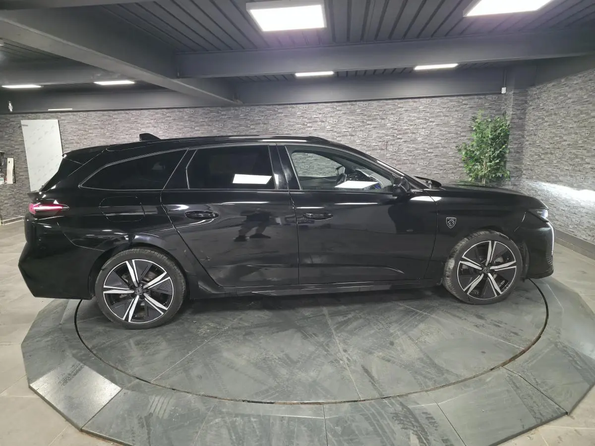 Peugeot 308 SW hybride noire vue de profil côté gauche, jantes alliage noires et toit noir brillant.