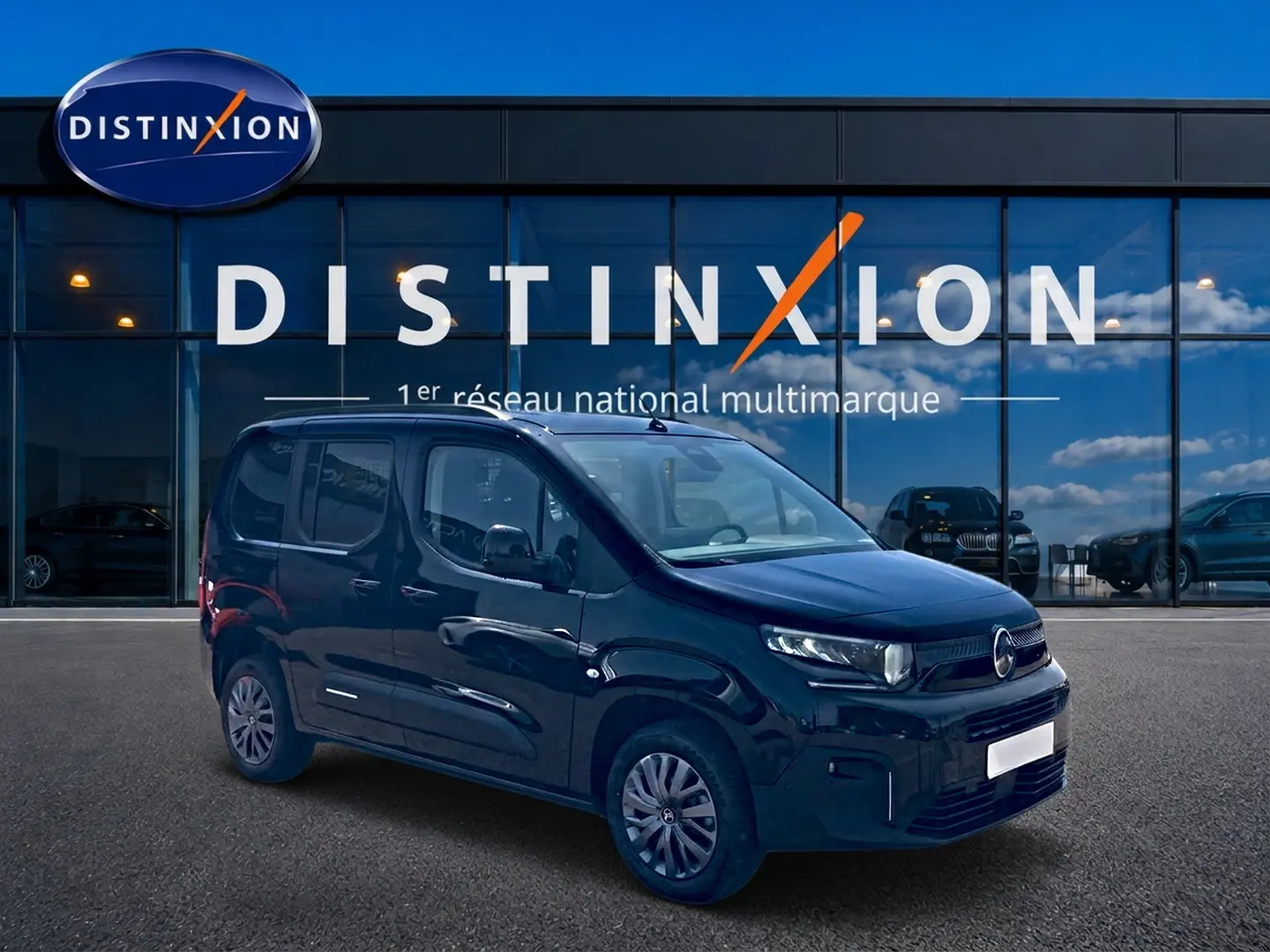 Vue 3/4 avant droite d'un Citroën Berlingo noir 2026 garé devant une vitrine avec logo Distinxion.