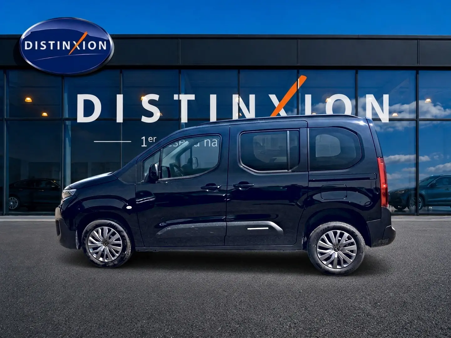 Vue de profil côté gauche d'un Citroën Berlingo noir 2026 devant une vitrine avec logo Distinxion.