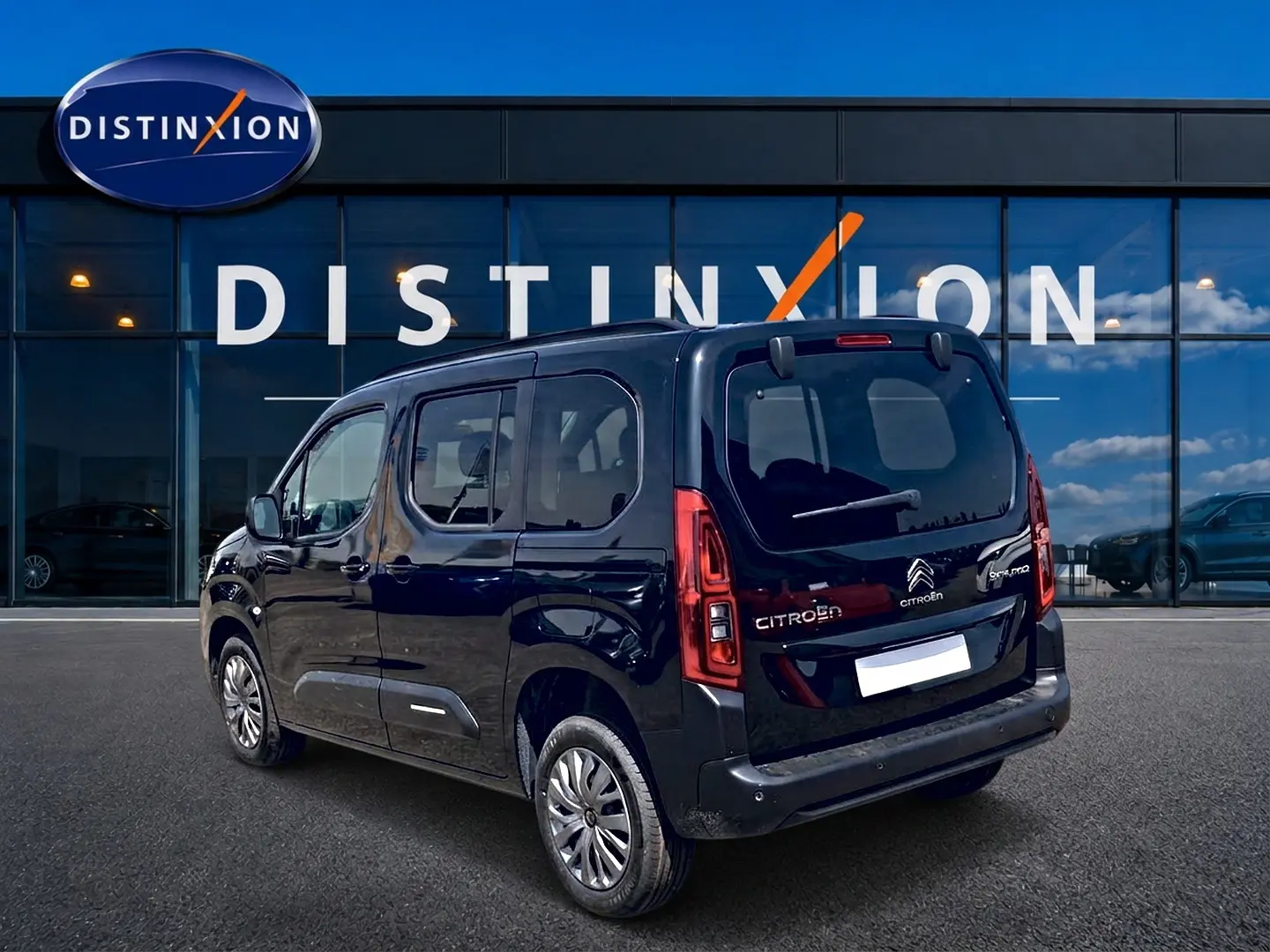 Citroën Berlingo noir vu en 3/4 arrière droit, avec vitres teintées et barres de toit visibles.