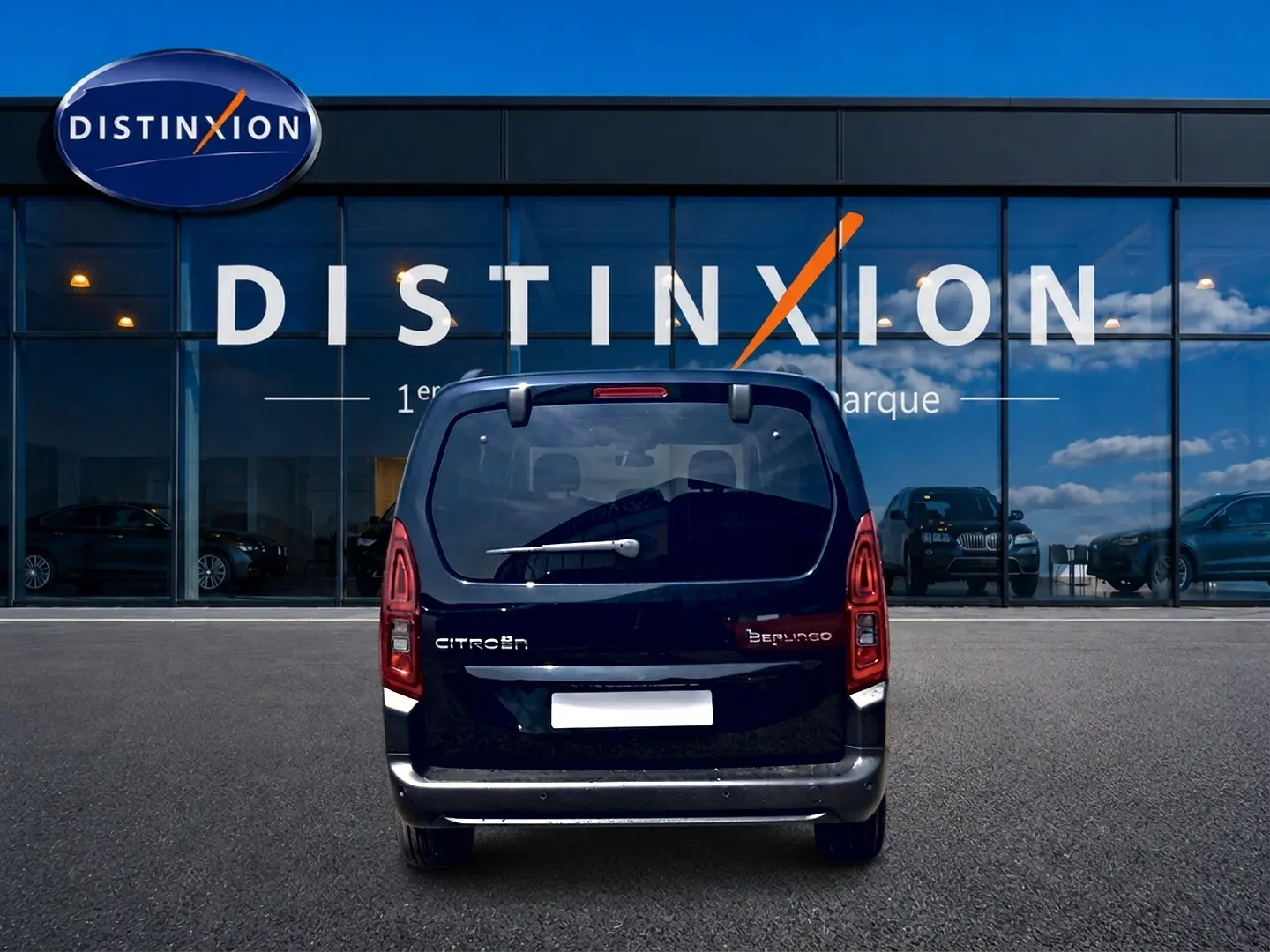Vue arrière d'un Citroën Berlingo noir 2026 garé devant une vitrine avec logo Distinxion.