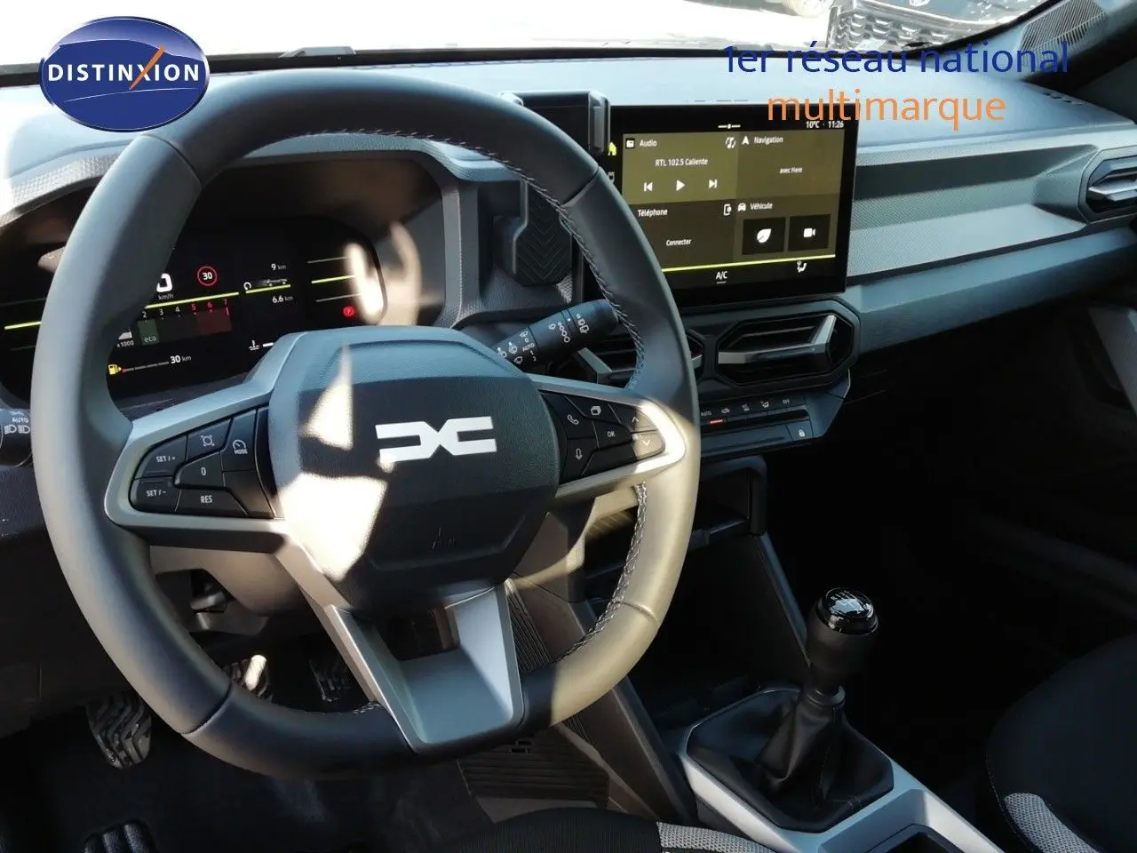 Vue intérieure du tableau de bord et volant du Dacia Duster 2026 avec boîte manuelle, finition gris noir et écran tactile central.