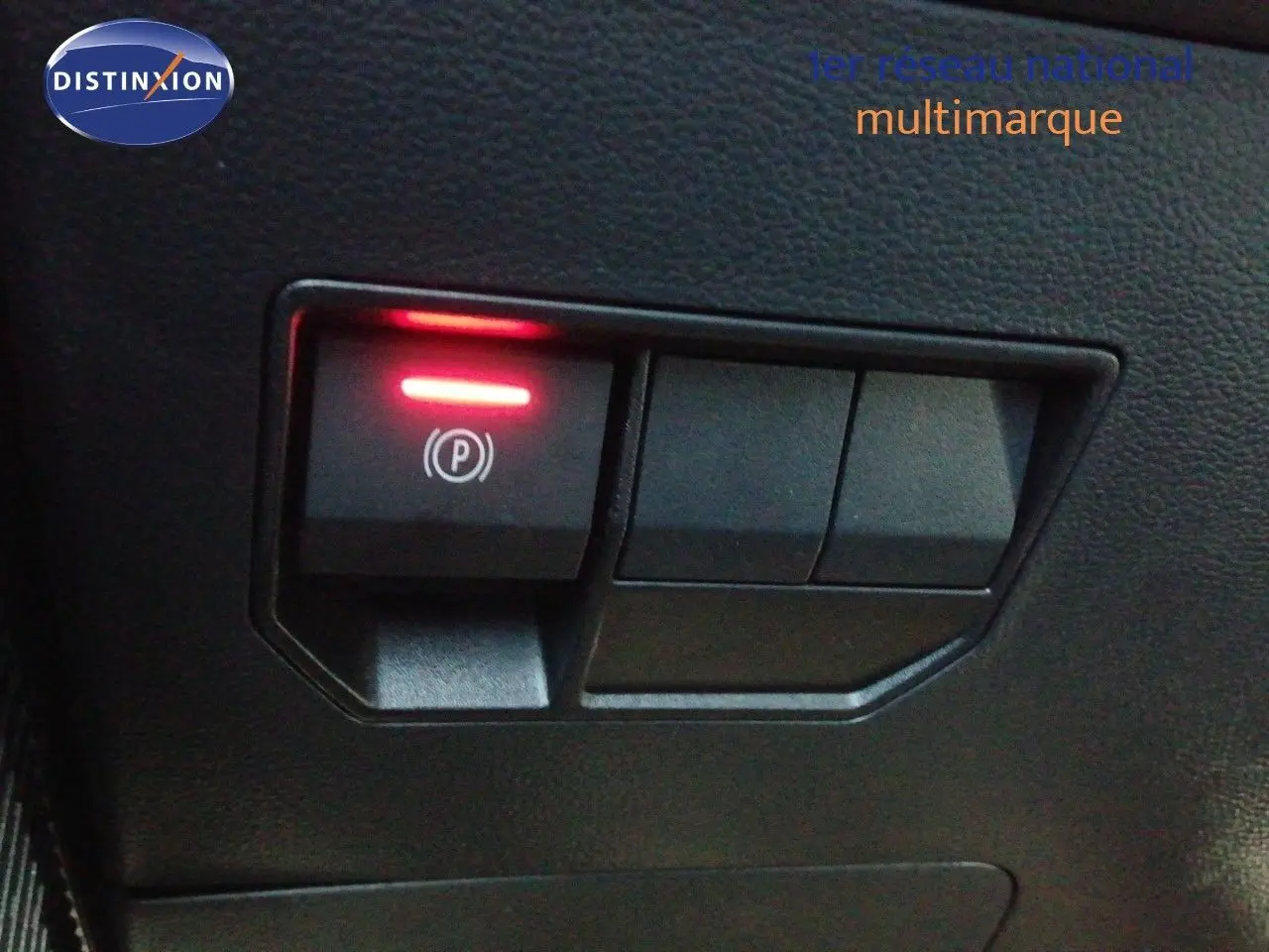 Détail intérieur du bouton de frein à main électronique allumé sur un Dacia Duster gris schiste métal 2026.