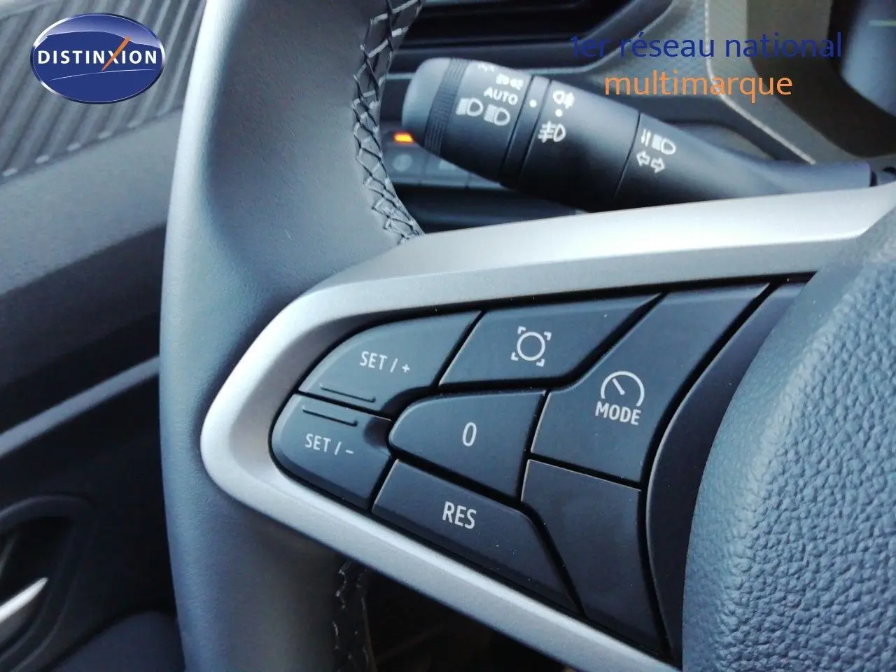 Gros plan sur les commandes au volant du Dacia Duster 2026 gris schiste métal, avec boutons de régulateur de vitesse.