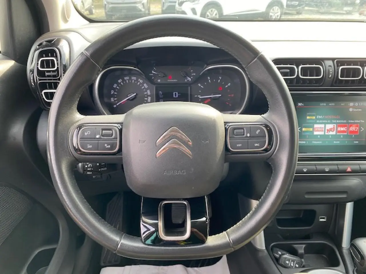 Vue intérieure centrée sur le volant en croûte de cuir du Citroën C3 Aircross noir avec tableau de bord et écran tactile.