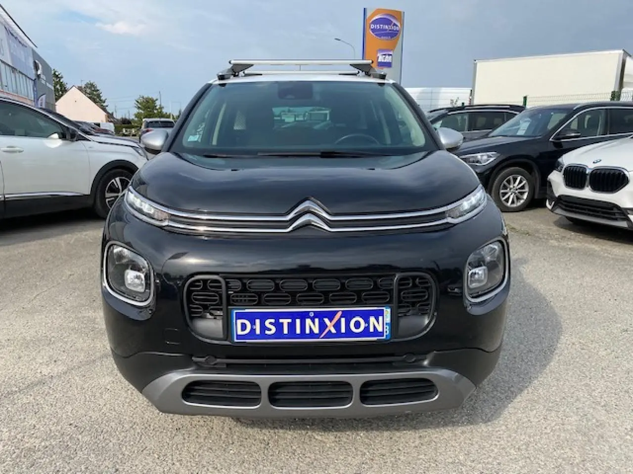 Vue de face d'un Citroën C3 Aircross noir 2019 avec toit blanc et barres de toit sur un parking.