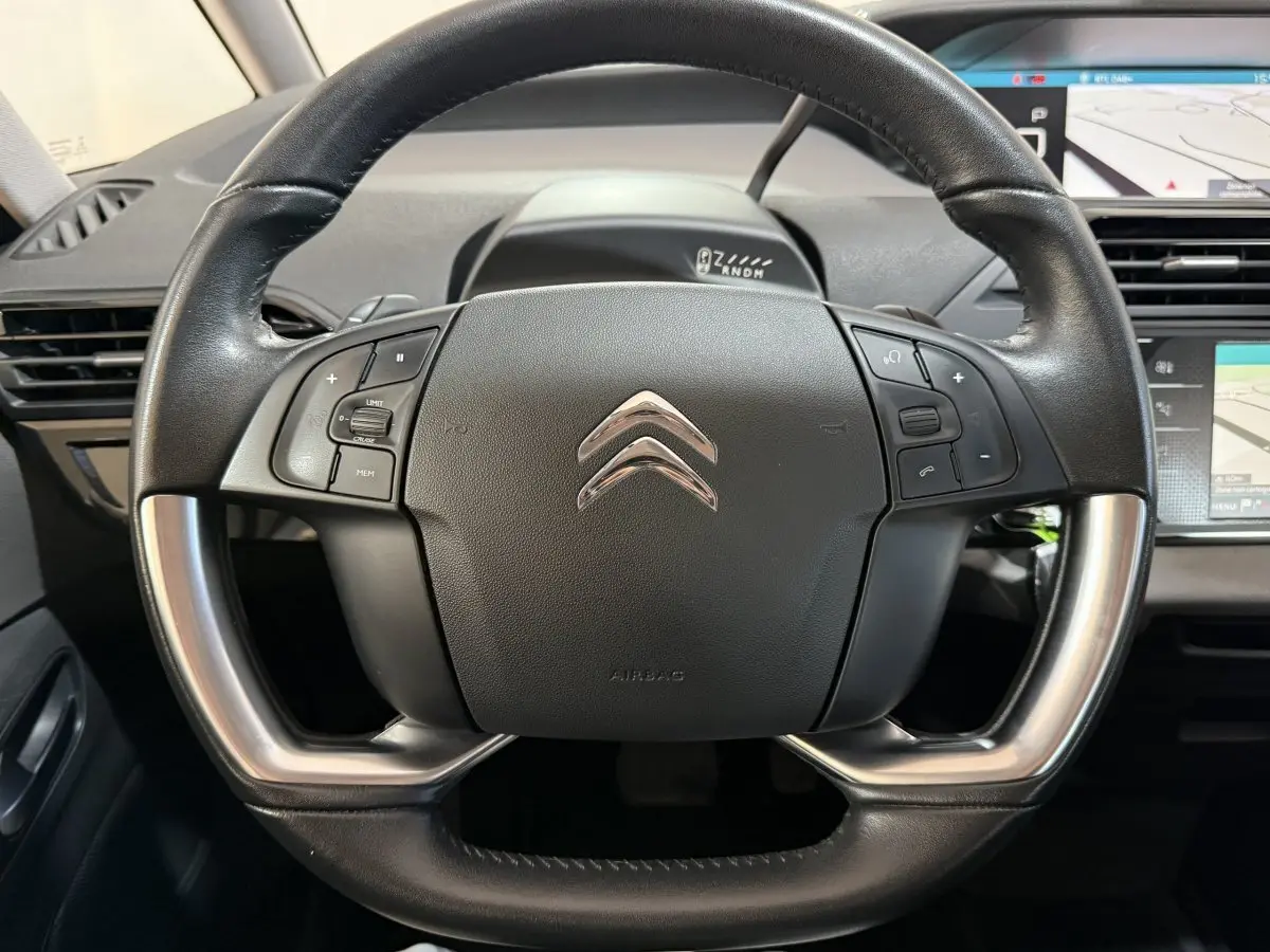 Vue rapprochée du volant cuir et alu noir du Citroën Grand C4 Spacetourer avec commandes intégrées et tableau de bord numérique.