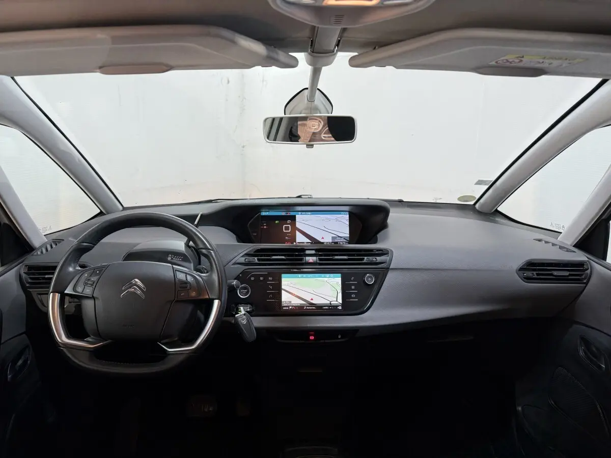 Vue intérieure avant du tableau de bord noir du Citroën Grand C4 Spacetourer blanc avec double écran tactile et volant multifonctions.