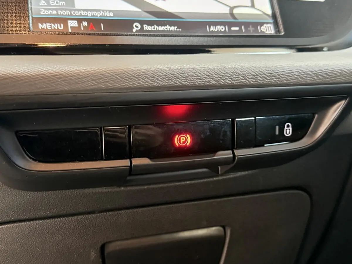 Gros plan sur le tableau de bord noir du Citroën Grand C4 Spacetourer 2021, bouton frein à main électrique allumé en rouge.