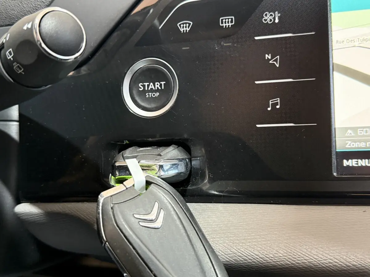 Gros plan intérieur sur le bouton Start/Stop et la clé Citroën insérée, avec partie de l’écran tactile visible.