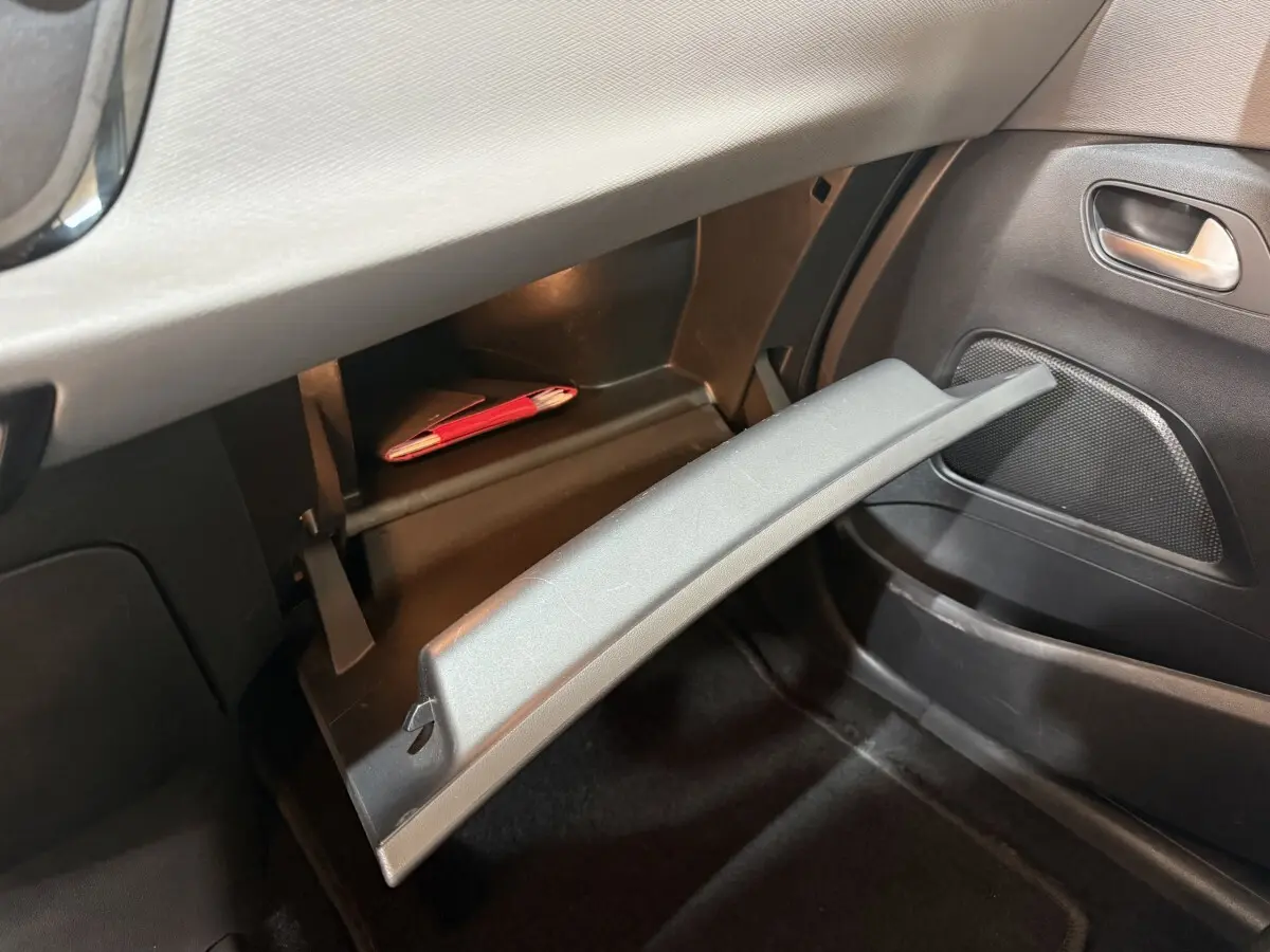 Ouverture de la boîte à gants côté passager dans l'habitacle noir du Citroën Grand C4 Spacetourer blanc 2021.